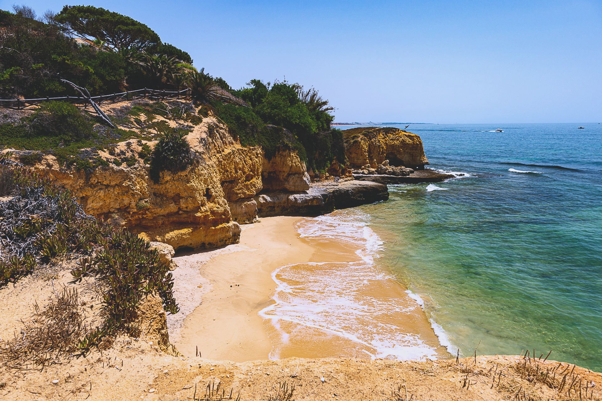 Eine kleine Sandbucht bei Albufeira, gerahmt von goldenen Klippen, mit brechenden Wellen am Ufer