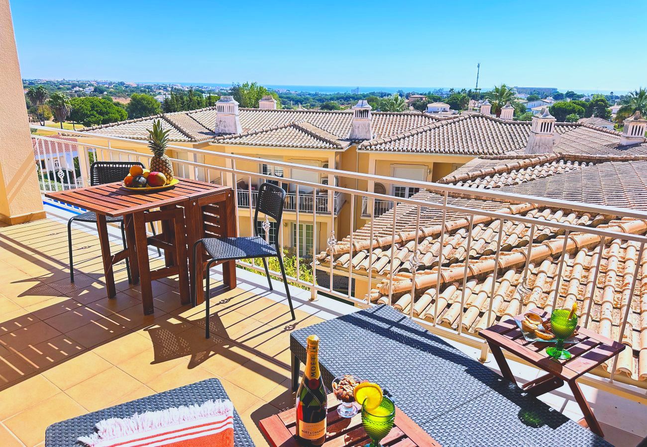 Ein Balkon mit Holztisch und Stühlen, mit Blick über die Dächer der Anlage