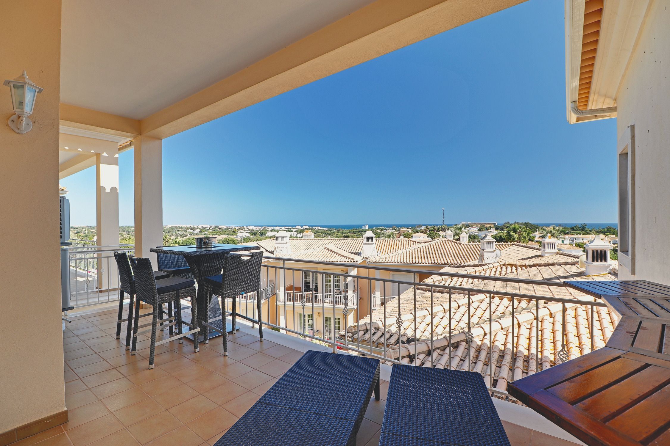 Überdachter Balkon des Casa Antonius mit Liegen und Stehtisch, mit Blick über die Ziegeldächer zum Atlantik am Horizont