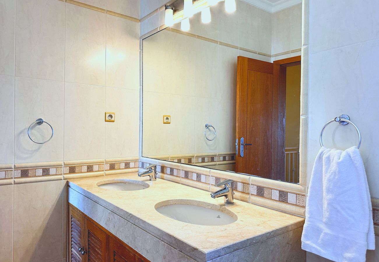 Ein Badezimmer mit zwei Waschbecken in einer Steinplatte unter einem raumbreiten Spiegel