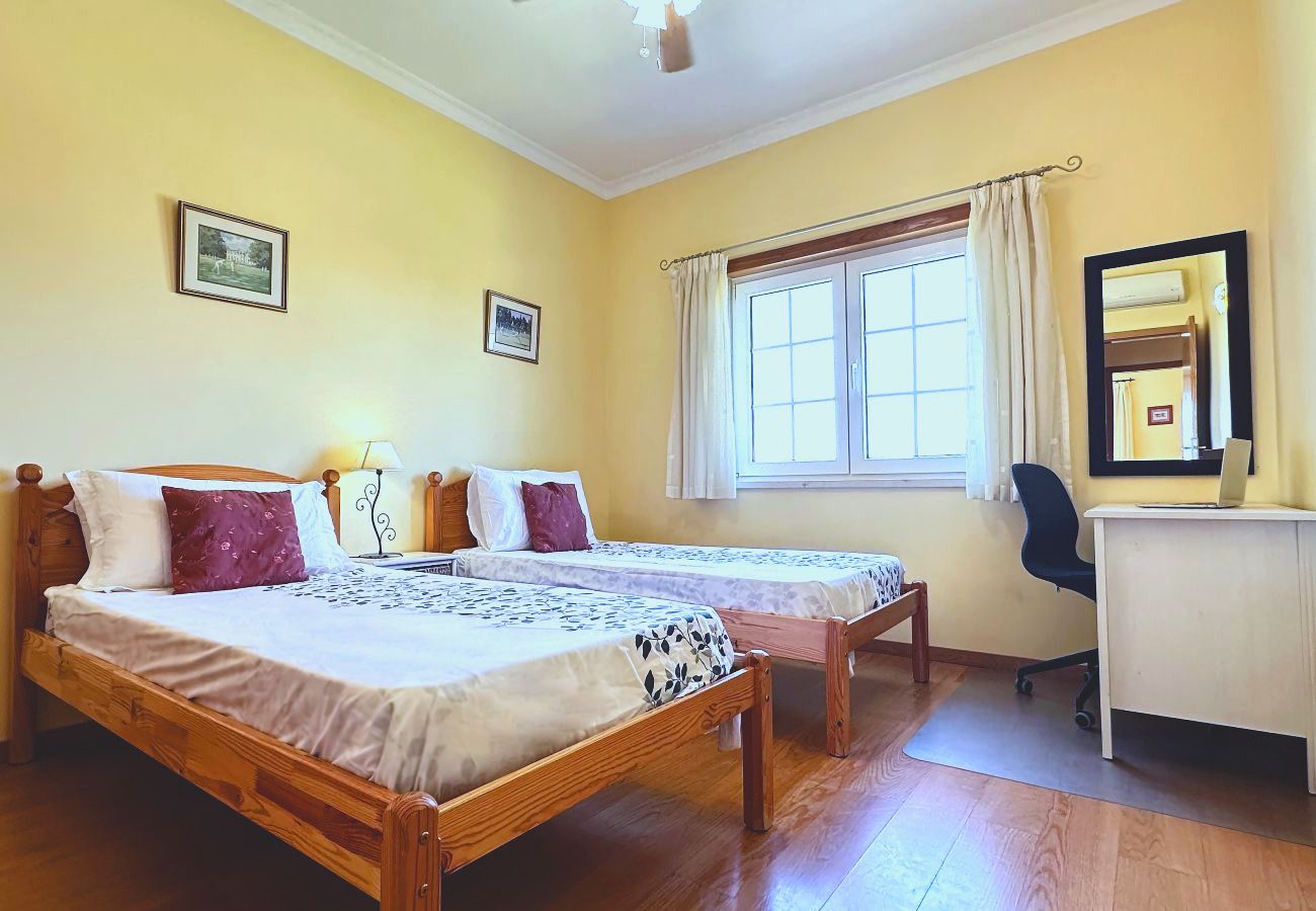 Das Zweibettzimmer von der Tür aus, mit zwei Einzelbetten, einem Schreibtisch und einem Bürostuhl am Fenster