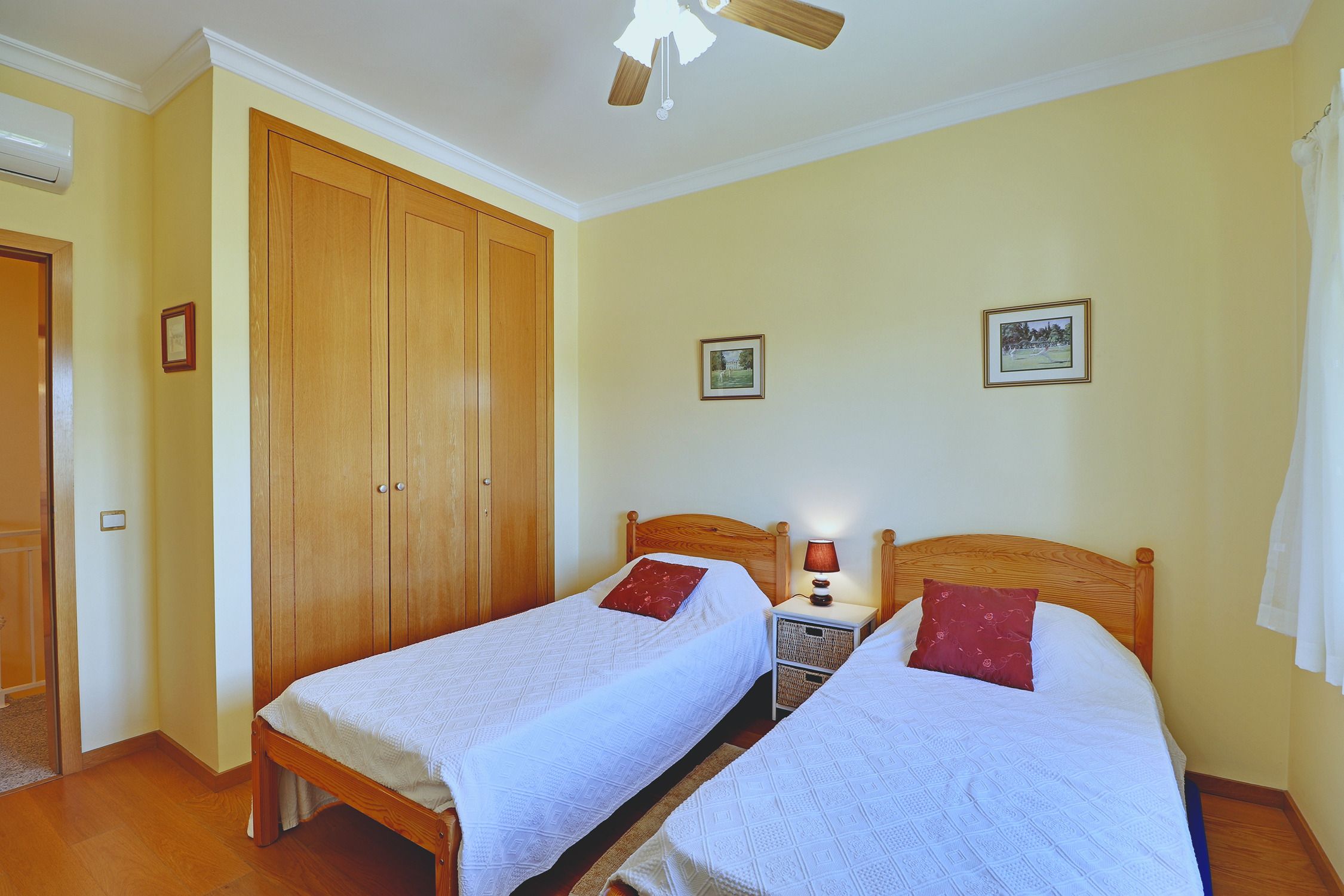 Das Zweibettzimmer mit zwei Einzelbetten, einem eingebauten Holzschrank und Deckenventilator