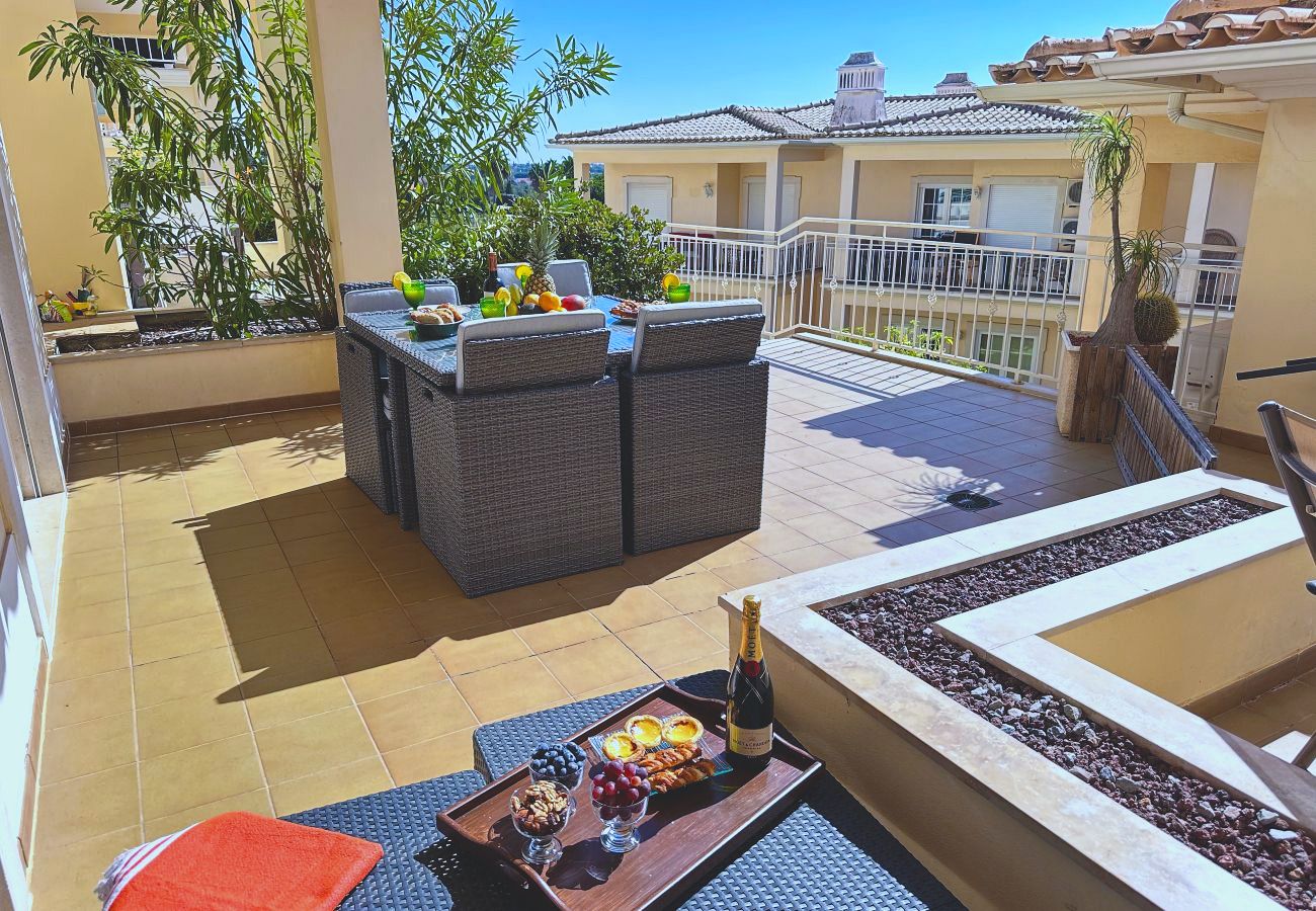 Die obere Terrasse mit Rattantisch und Stühlen, Pflanzkübeln und Blick über die benachbarten Dächer